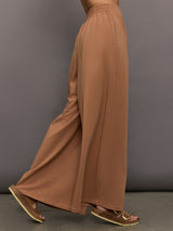 Model wears a pair of oversized, wide legged, light brown sweatpants.
