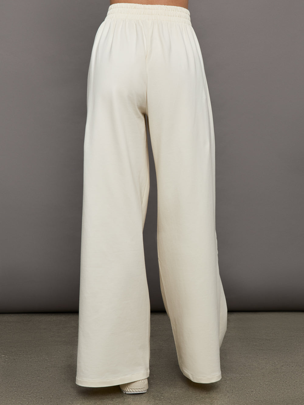 Model wears a pair of oversized wide leg cream colored sweatpants. 
