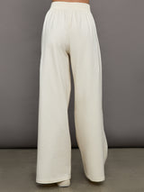 Model wears a pair of oversized wide leg cream colored sweatpants. 