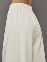 Model wears a pair of oversized wide leg cream colored sweatpants. 