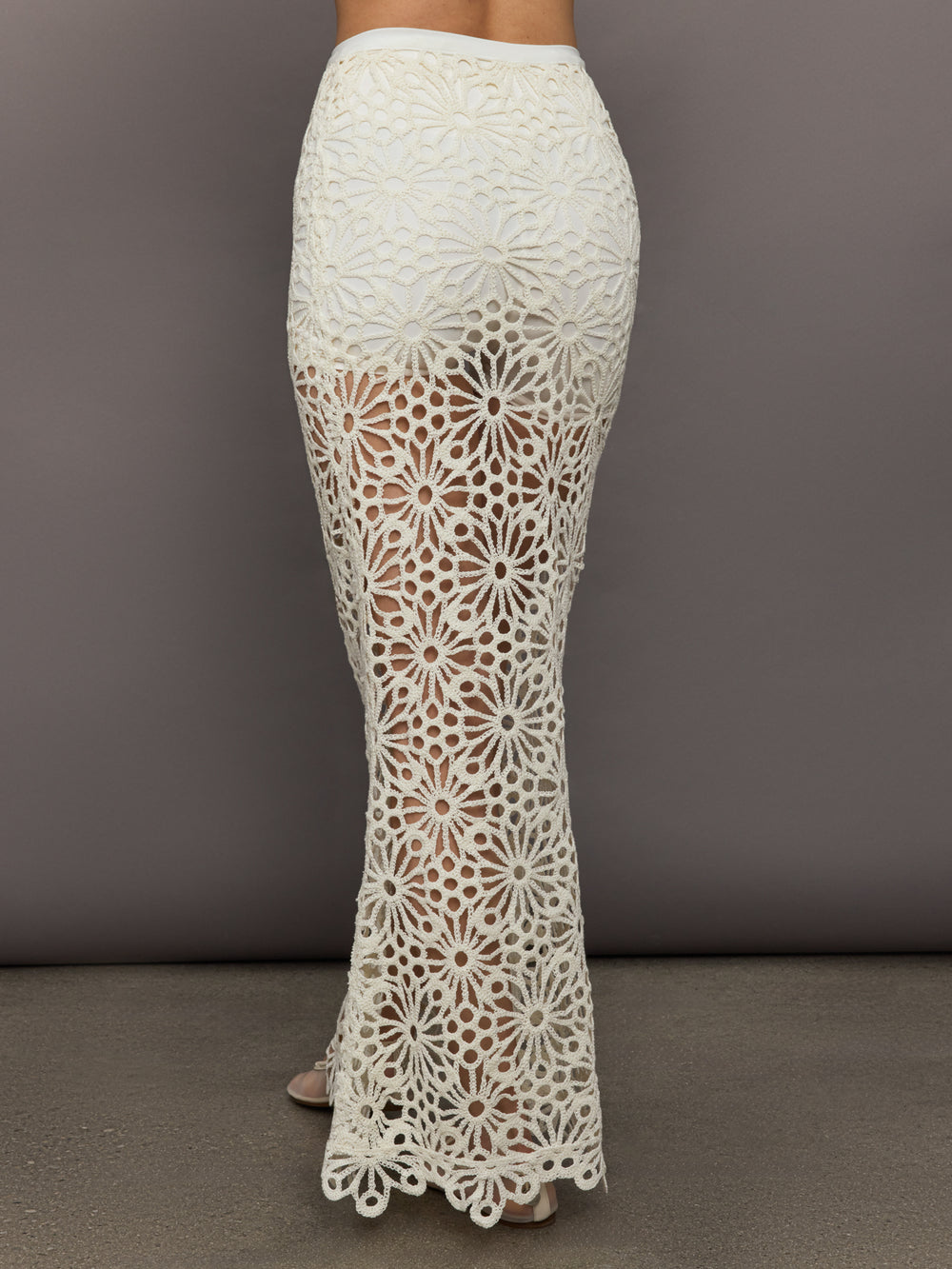 Model wears the Obie Long Skirt in cream, with a high waist, flower detailing and flared bottom.