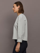 Model is wearing Bomber 1980s Sweatshirt in Light Heather Grey, side profile view.