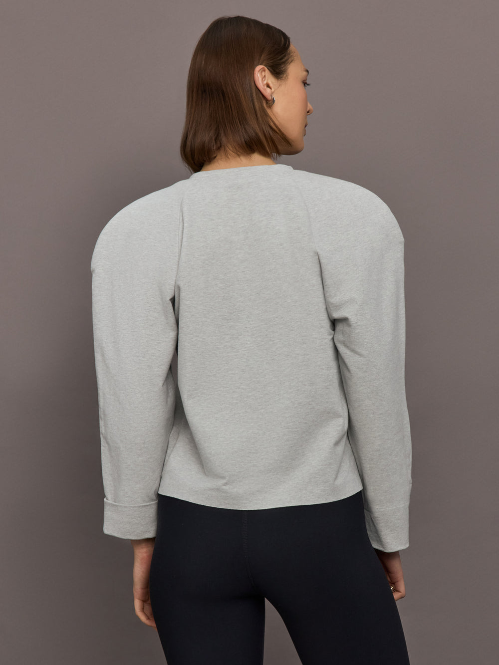 Model is wearing Bomber 1980s Sweatshirt in Light Heather Grey, back view.