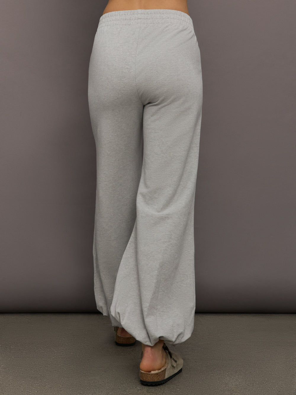 Model is wearing Boyfriend Puff Jog Pant in Light Heather Grey, back view.