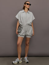 Model is wearing Super Oversized Sleeveless NK Bodysuit in Light Heather Grey, full body styling with shorts.