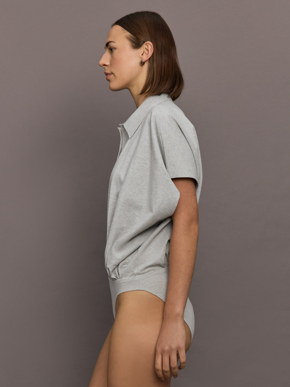 Model is wearing Super Oversized Sleeveless NK Bodysuit in Light Heather Grey, side profile view.