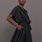 Model wears the Super OS Sleeveless BF NK Shirt Flared Mini Dress in Black with a flared skirt, belted waist and collared neckline.