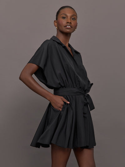 Model wears the Super OS Sleeveless BF NK Shirt Flared Mini Dress in Black with a flared skirt, belted waist and collared neckline.
