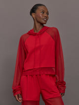 Model wears the Oversized Raglan Sleeve Hooded Cropped Top in Tiger Red, with mesh raglan sleeves and a mesh hood with a breathable design with a relaxed fit.