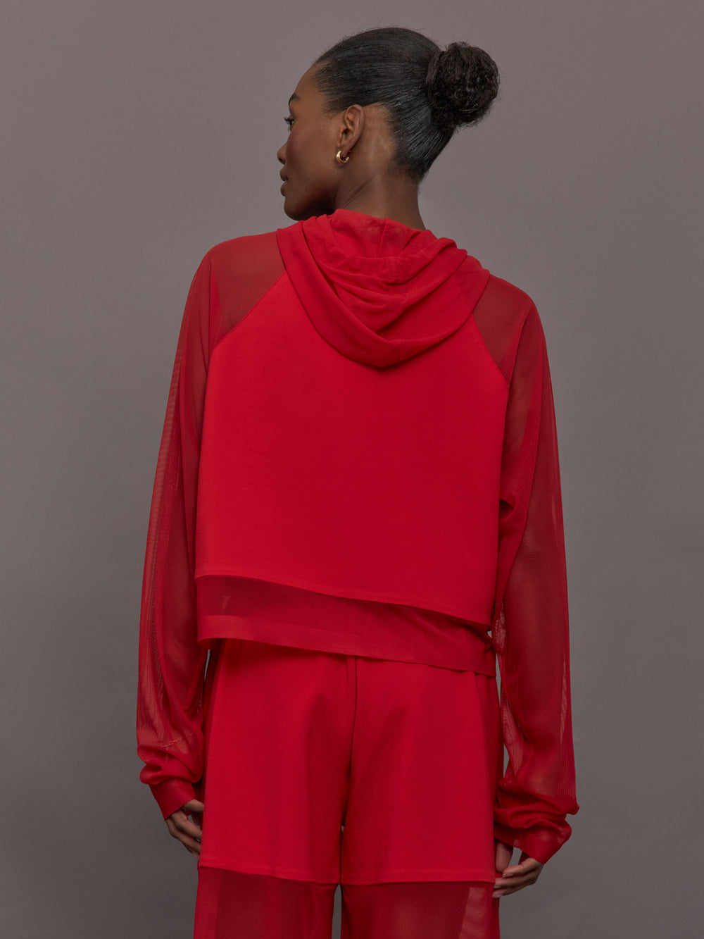 Model wears the Oversized Raglan Sleeve Hooded Cropped Top in Tiger Red, with mesh raglan sleeves and a mesh hood with a breathable design with a relaxed fit.