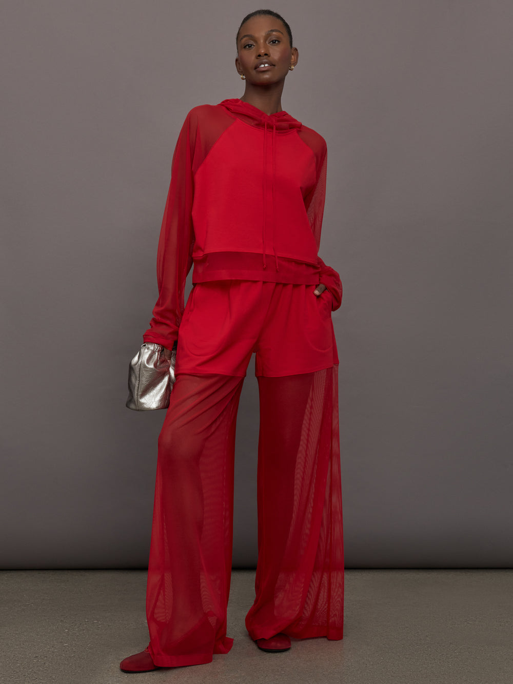 Model wears the Oversized Raglan Sleeve Hooded Cropped Top in Tiger Red, with mesh raglan sleeves and a mesh hood with a breathable design with a relaxed fit.