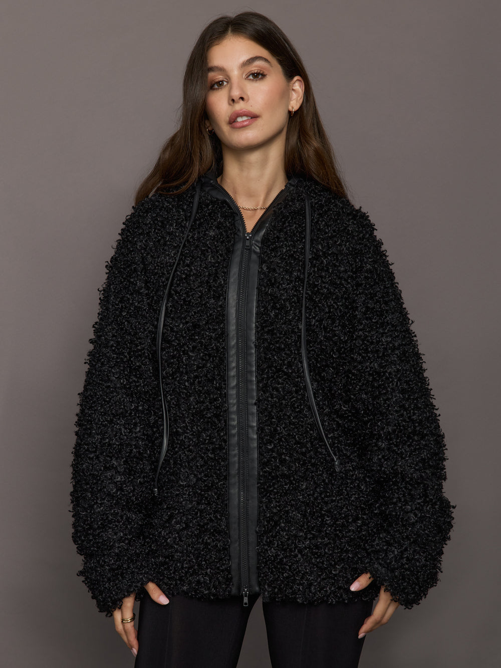 Woman wearing a black textured jacket against a gray background