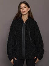 Woman wearing a black textured jacket against a gray background