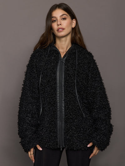 Woman wearing a black textured jacket against a gray background