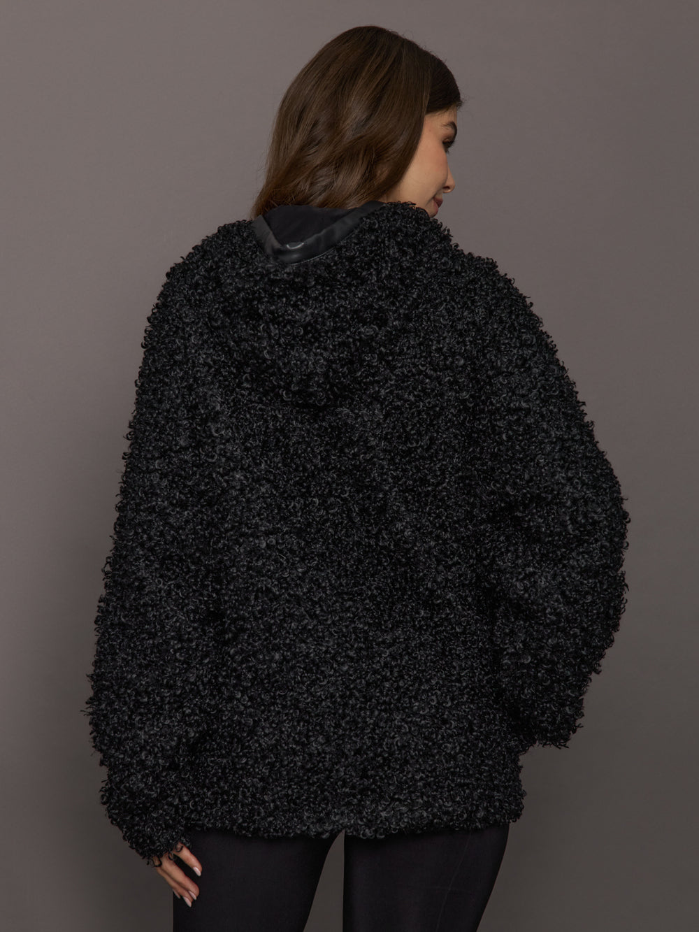 Person wearing a black textured jacket against a gray background