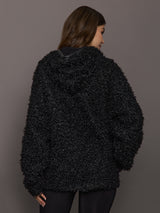 Person wearing a black textured jacket against a gray background