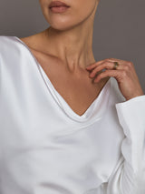 Close-up of a person wearing a white satin garment with a neutral background