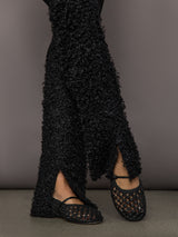 Black textured leggings with a slit and matching shoes on a plain background