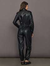Person wearing a black leather jumpsuit against a gray background