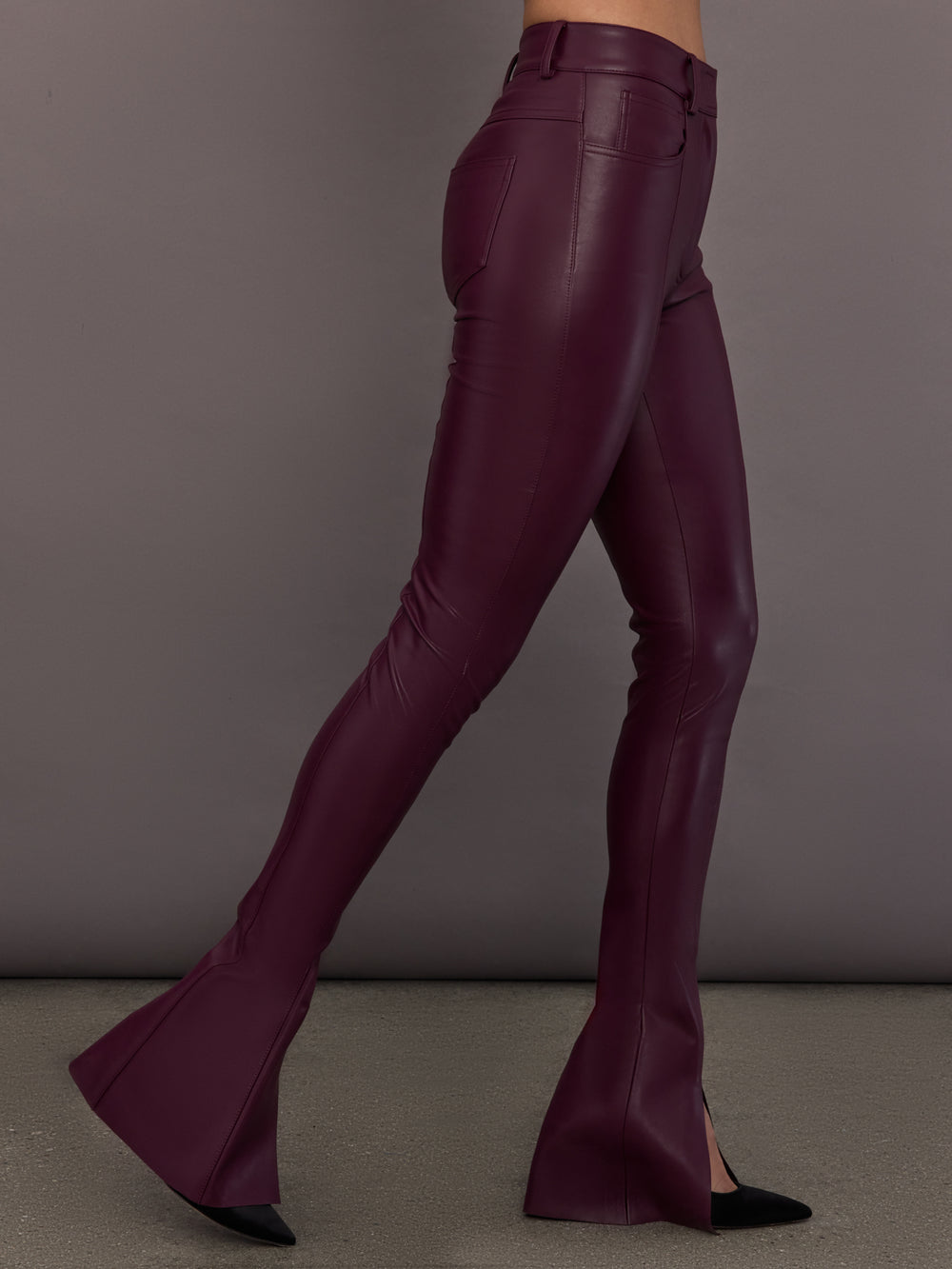 Model is wearing the Spat Jeans in Plum, side view showing slim leg and slit.