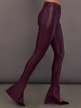 Model is wearing the Spat Jeans in Plum, side view showing slim leg and slit.