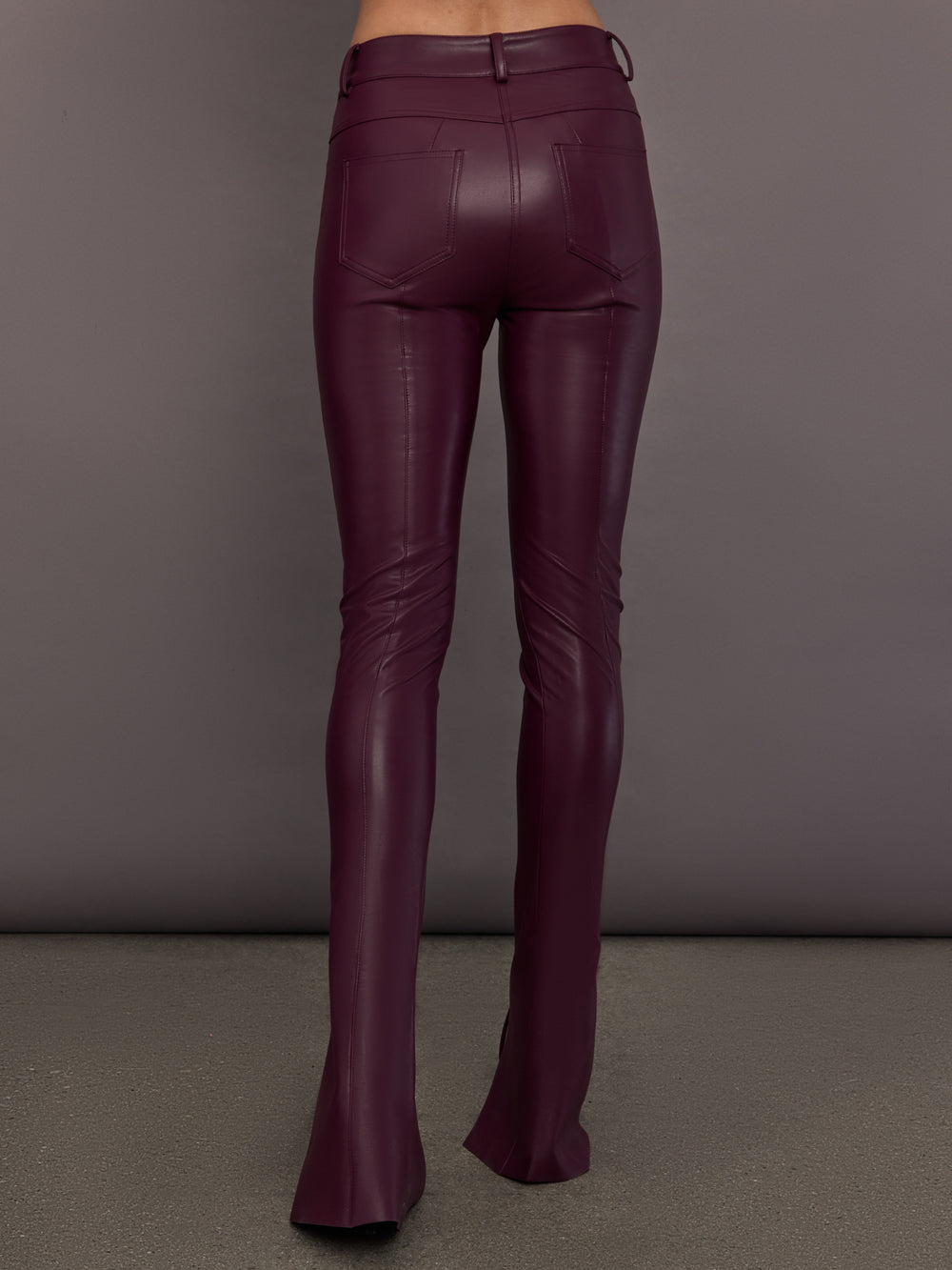 Model is wearing the Spat Jeans in Plum, back view with pocket detail.