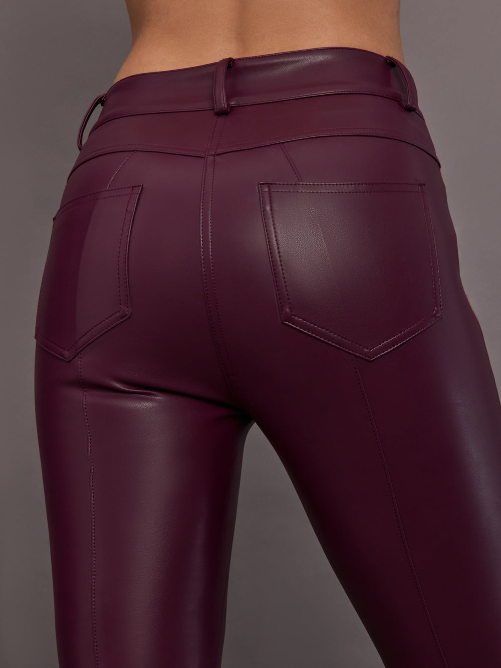 Model is wearing the Spat Jeans in Plum, close-up of vegan leather texture.