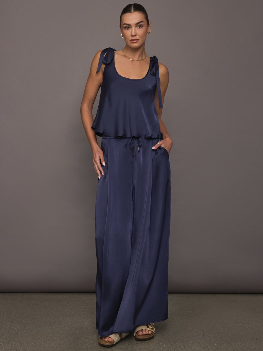 Model wearing Satin Tie Shoulder Tank Top in navy styled with drawstring pants, front view.