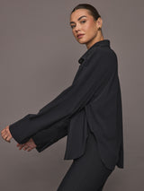 Model wearing Oversized Stretch Button-Down Shirt in black, side view.
