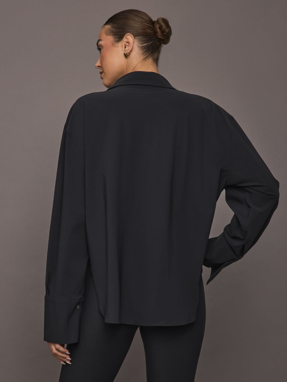 Model wearing Oversized Stretch Button-Down Shirt in black, back view.