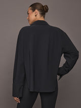 Model wearing Oversized Stretch Button-Down Shirt in black, back view.