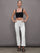 Model wearing cropped white flare pants styled with black crop top, full body view.