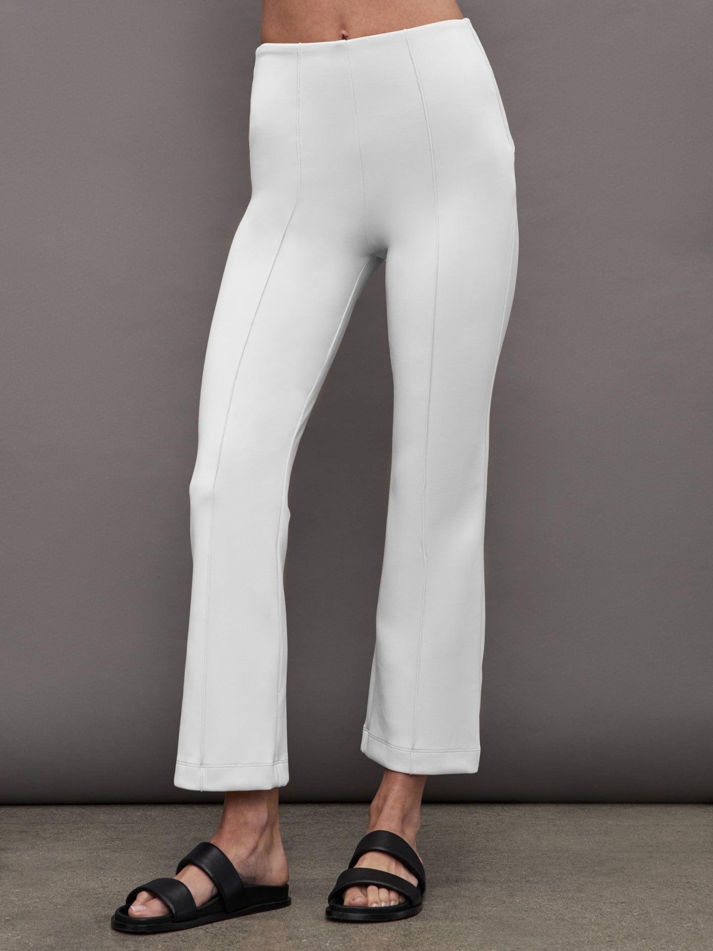 Model wearing cropped white flare pants with pintuck detail, front view.