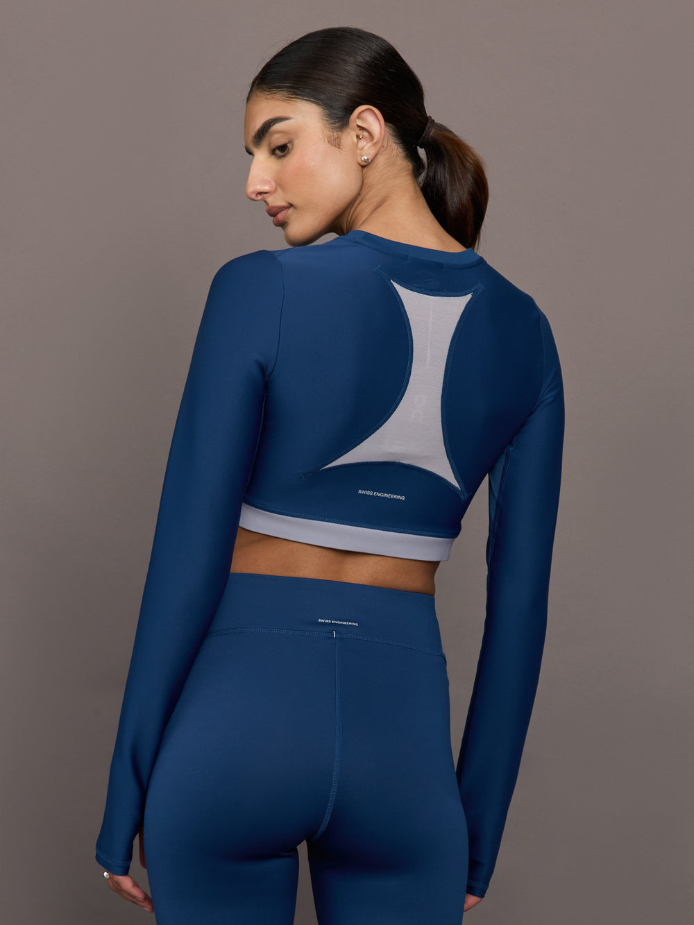 Woman wearing a blue athletic outfit with a gray geometric design on a gray background