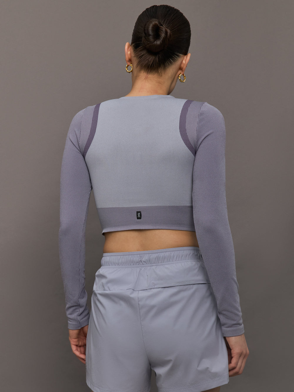 Model wears lilac cropped long-sleeve top with a fitted knit texture, with a high neckline and a snug, athletic fit.