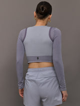 Model wears lilac cropped long-sleeve top with a fitted knit texture, with a high neckline and a snug, athletic fit.