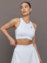 Model wears white cropped tank top with wide shoulder straps and a high neckline.