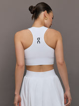 Model wears white cropped tank top with wide shoulder straps and a high neckline.