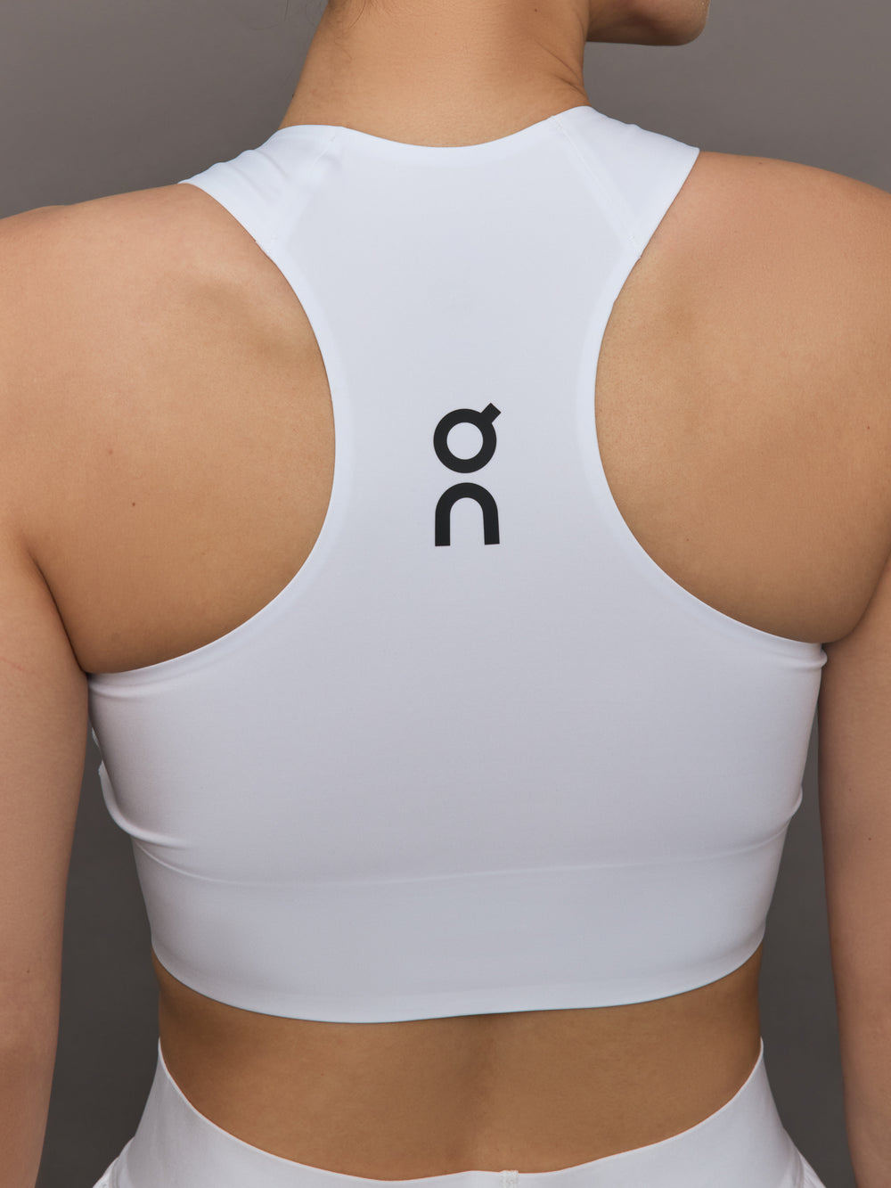 Model wears white cropped tank top with wide shoulder straps and a high neckline.