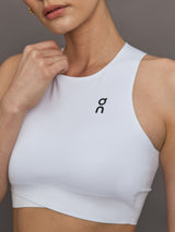 Model wears white cropped tank top with wide shoulder straps and a high neckline.