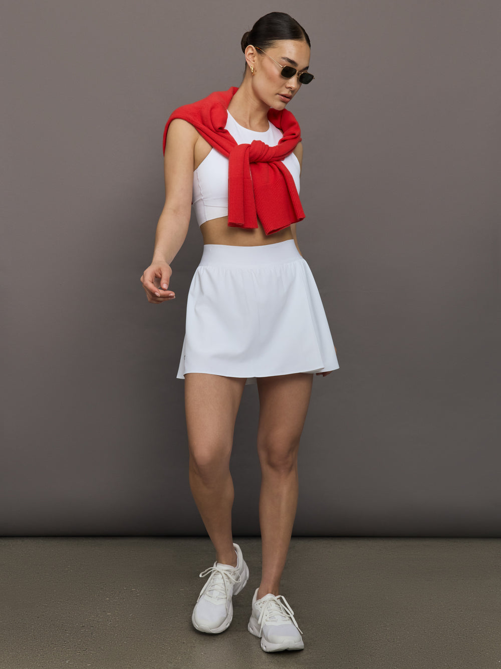 Model wears white cropped tank top with wide shoulder straps and a high neckline.