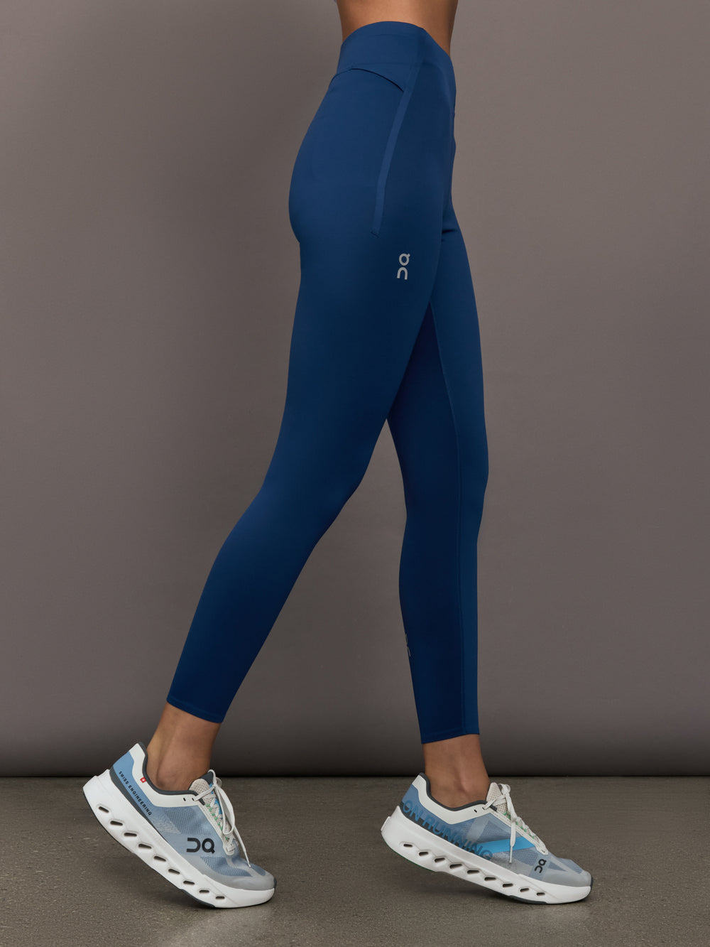 Person wearing blue leggings and white sneakers on a gray background