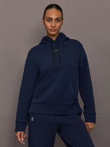 Model is wearing On Focus Tech Hoodie for women in navy with drawstring hood, kangaroo pocket, and relaxed fit, front view.