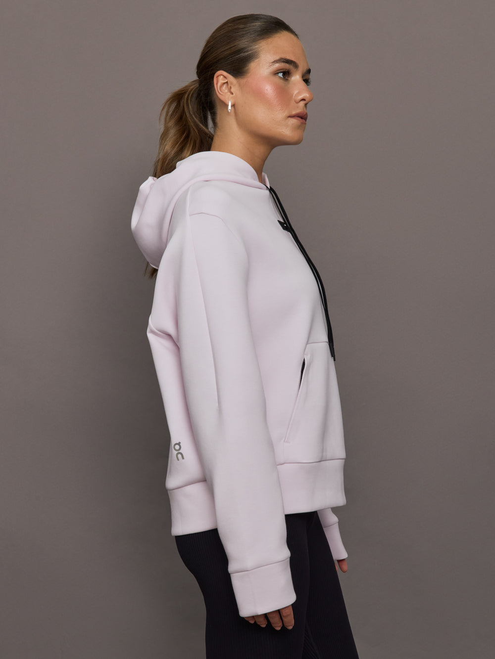 Woman wearing a light purple hoodie against a gray background