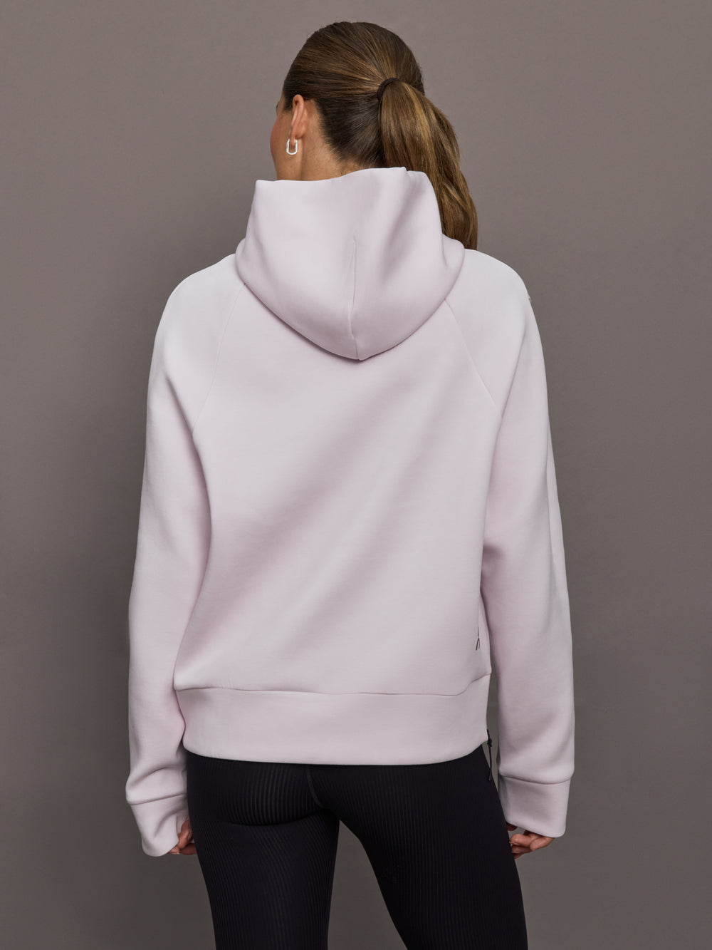 Person wearing a light purple hoodie from behind on a gray background