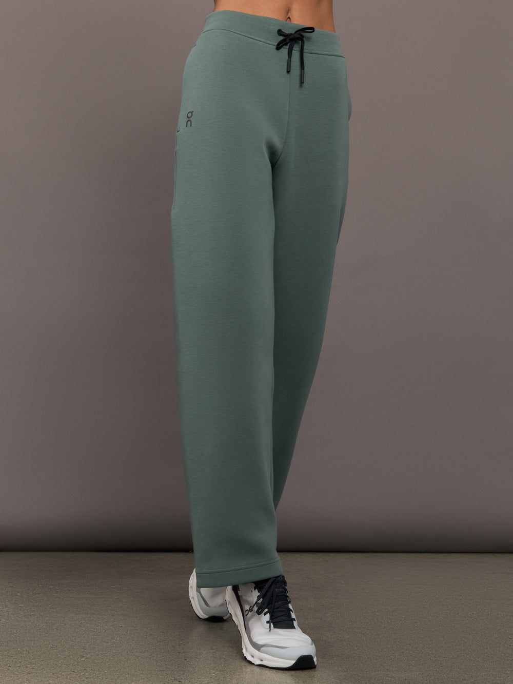 Green sweatpants worn by a person on a gray background