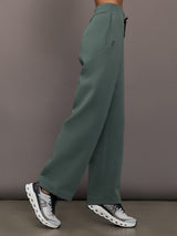 Green sweatpants worn by a person on a plain background