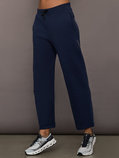 Model is wearing On Focus Tech Sweatpants for women in navy with drawstring waist, straight leg, and side pockets, front view.