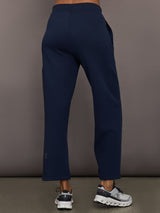 Model is wearing On Focus Tech Sweatpants for women in navy with clean back design, straight leg fit, and ankle-length cut, back view.