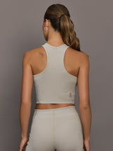 Model wears a high neck sleeveless cropped top in light sandy brown. 